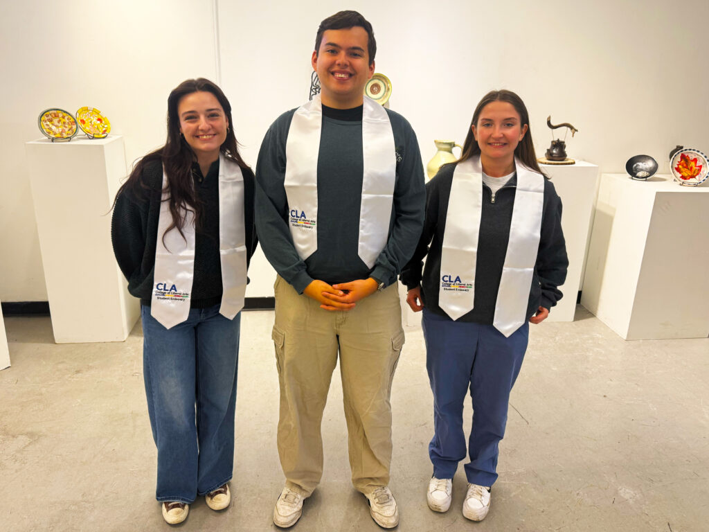 Three student emissaries pose for a photo with their CLA Graduation Cords. 