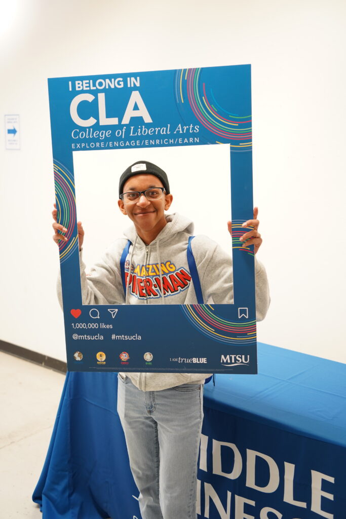 Admitted student holding photo frame that says "I Belong In CLA"